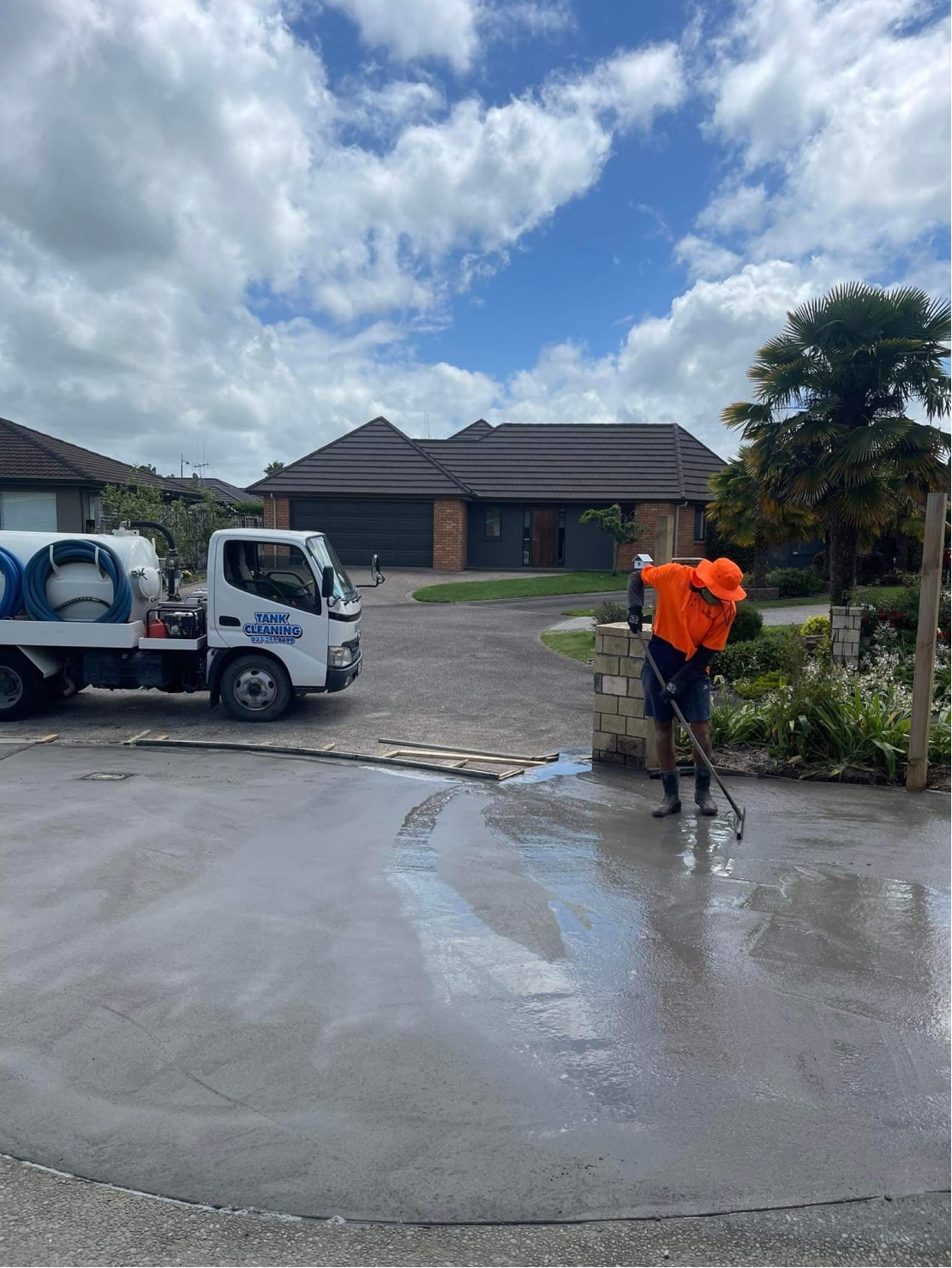 Person Cleaning Up Water on Driveway